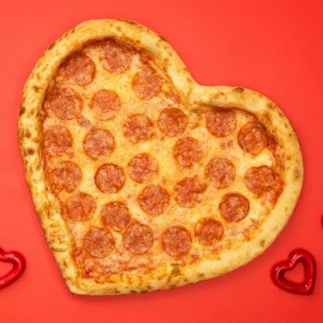 kırmızı kağıt arka planda sevgililer günü için kalp şeklinde pizza biberli
