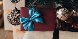 Noel ağacının altında mavi fiyonklu bordo zarfta hediye çeki Noel hediyesi